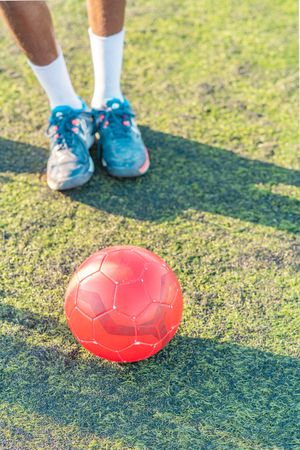 Football ball on lawn near anonymous athlete
