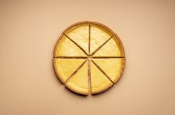 Cheesecake cut in 8 equal slices on a brown table