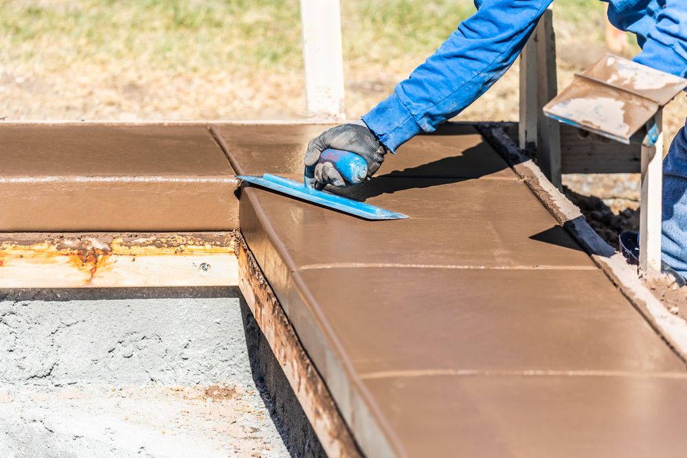 Construction Worker Using Trowel On Wet Cement Forming Coping Around New Pool