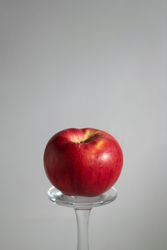 Red apple balancing on glass