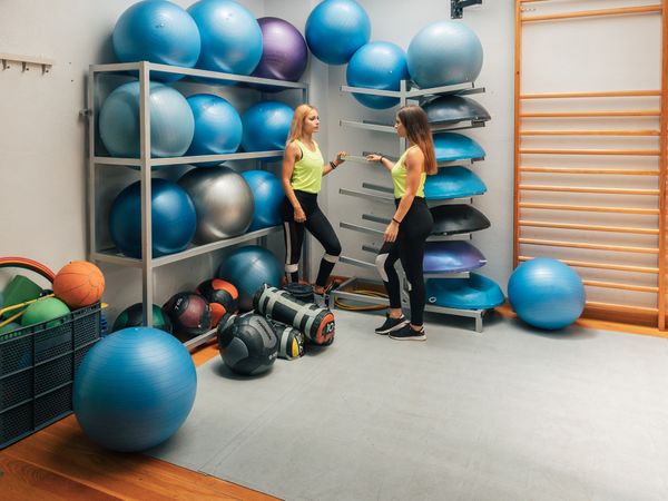 Sportswomen standing near equipment rack in gym