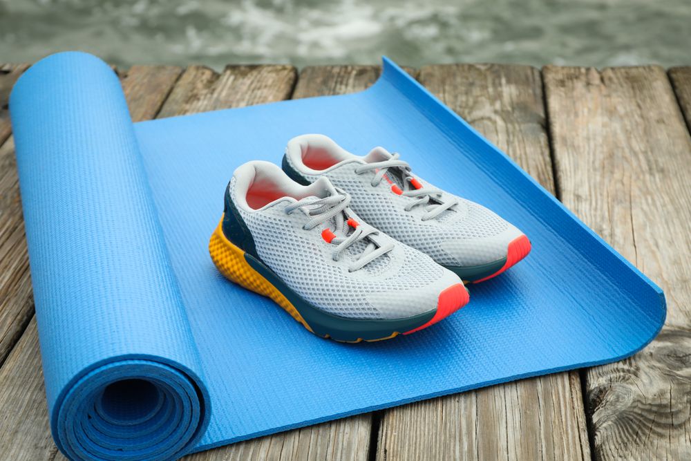 Karemat and sneakers on wooden floor outdoors