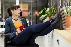 Smiling businesswoman with mug resting in office