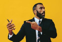 Frustrated Black businessman having a video call on a smartphone screen and pointing