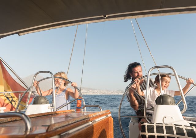 Man with boy and girl holding steering wheel on yacht on water