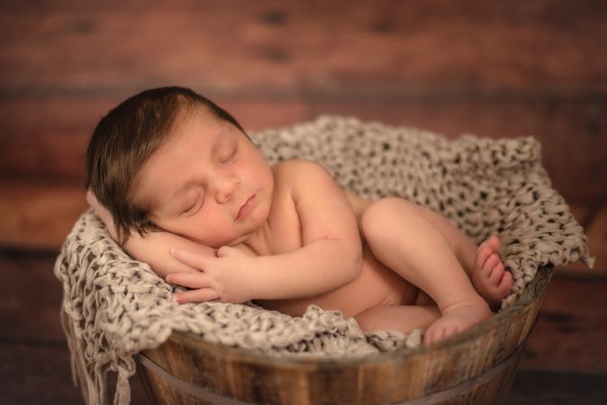 Naked baby sleeping in bucket