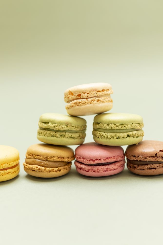 Pile of sweet pastel macaroons over a green background