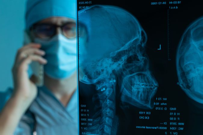 Doctor consulting patient on the phone while examining X-ray