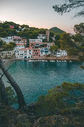 Sailboats on sea water against houses on rocky shore