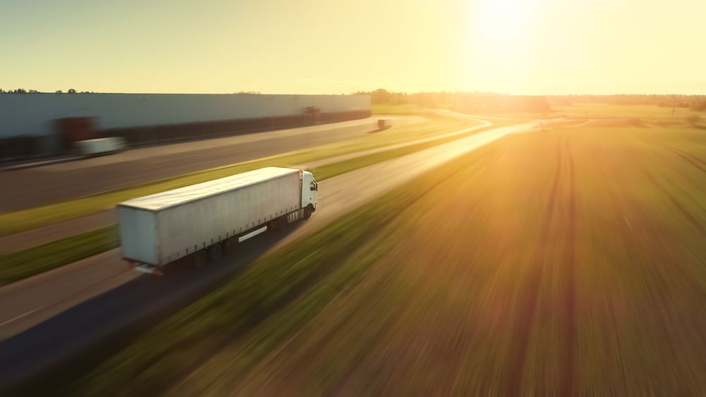 Aerial Follow Shot of Semi Truck with Cargo Trailer Attached Moving Through Industrial Warehouse