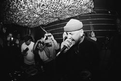 Portrait of young man in beanie singing into microphone