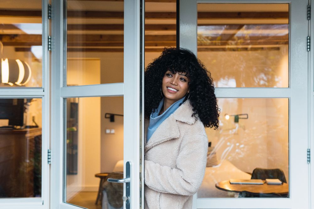 Happy Black woman standing in doorway of house
