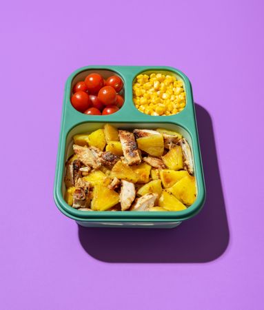 Lunch box with summer salad on a purple background