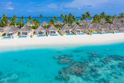 Holiday villas line the beach in the Maldives, with copy space
