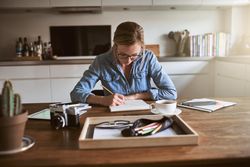Woman sketching at kitchen table with coffee