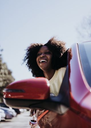 Woman with afro hair peeking out of the car .