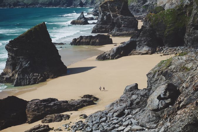 Two people walking on a rocky beach