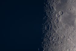 Detailed lunar craters visible near moon's shadow terminator line.
