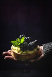 Hand holding a blackberry tartlet