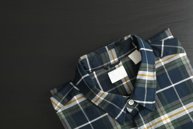 Folded checkered shirt on table, space for text
