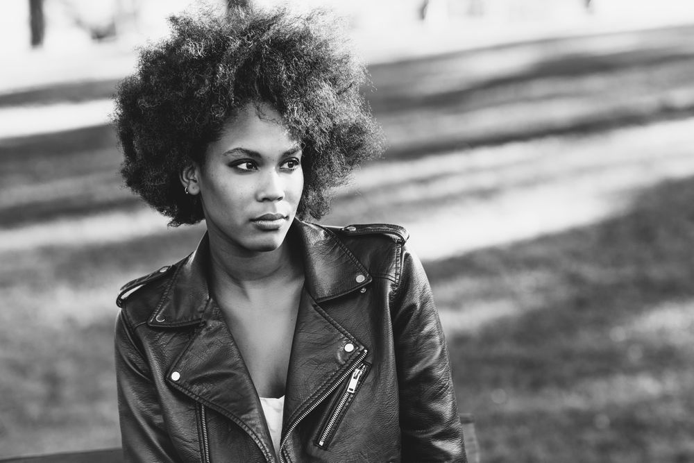 B&W shot of woman sitting outside looking in the distance