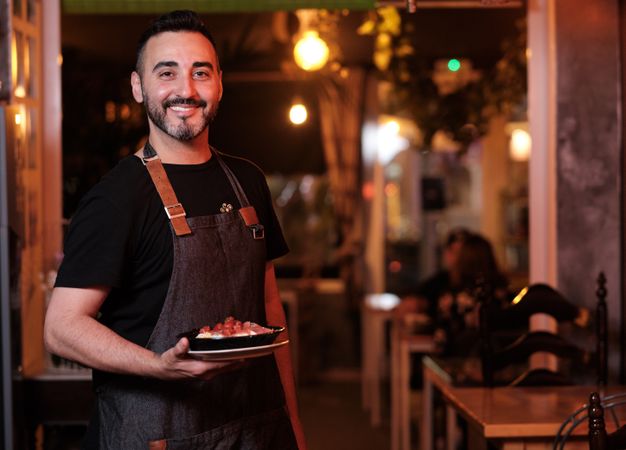 Cheerful waiter serving snack in restaurant