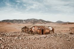 Dilapidated old buildings in mountain desert under cloudy sky