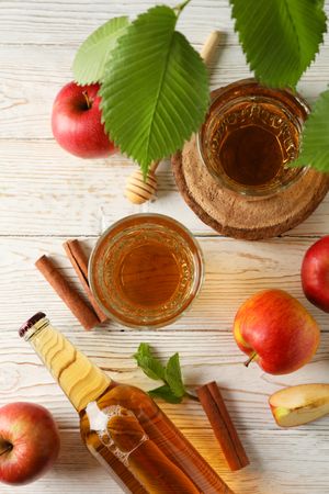 Composition with cider, cinnamon and apples on wooden background