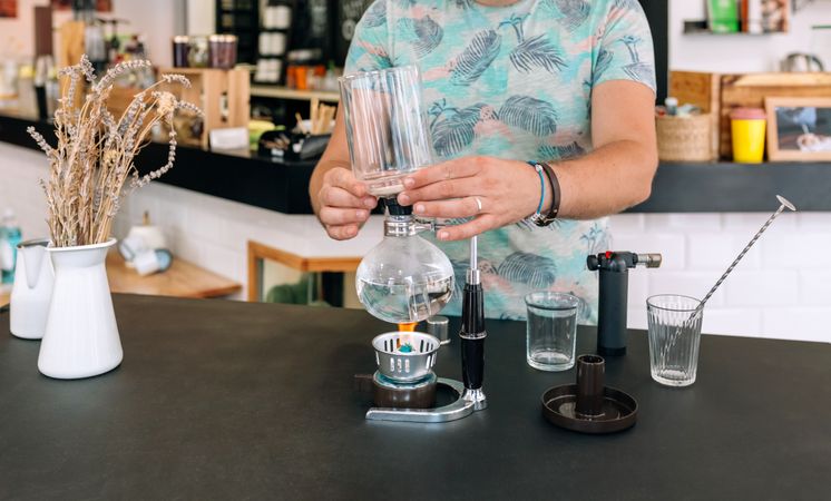 Unrecognizable barista skillfully preparing specialty coffee using Japanese siphon