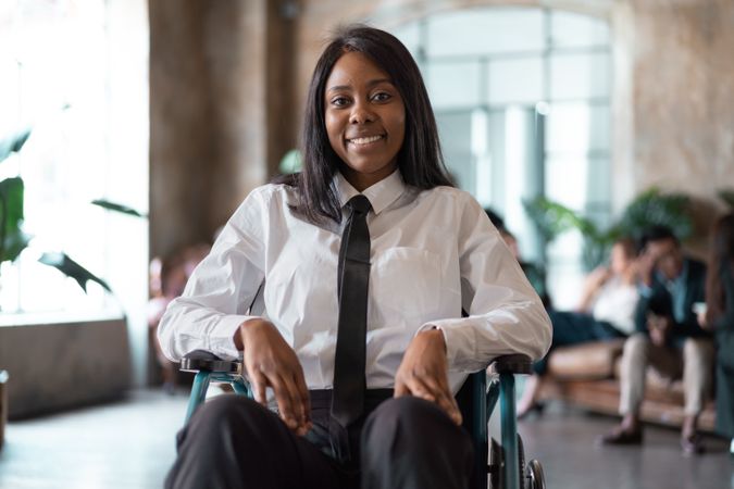 Portrait of a woman with a disability in a wheelchair smiling in her office lobby