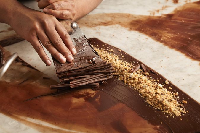 Picture of hands creating chocolate shavings on marble counter