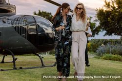 Women friends walking away from helicopter with wine 5aXP8A