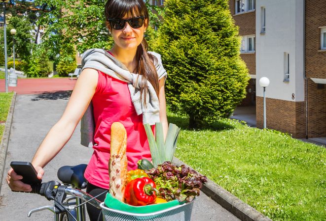 Young sportive woman with groceries in a basket bike