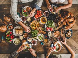 Group of people serving themselves at Turkish style breakfast with eggs, breads, vegetables and tea