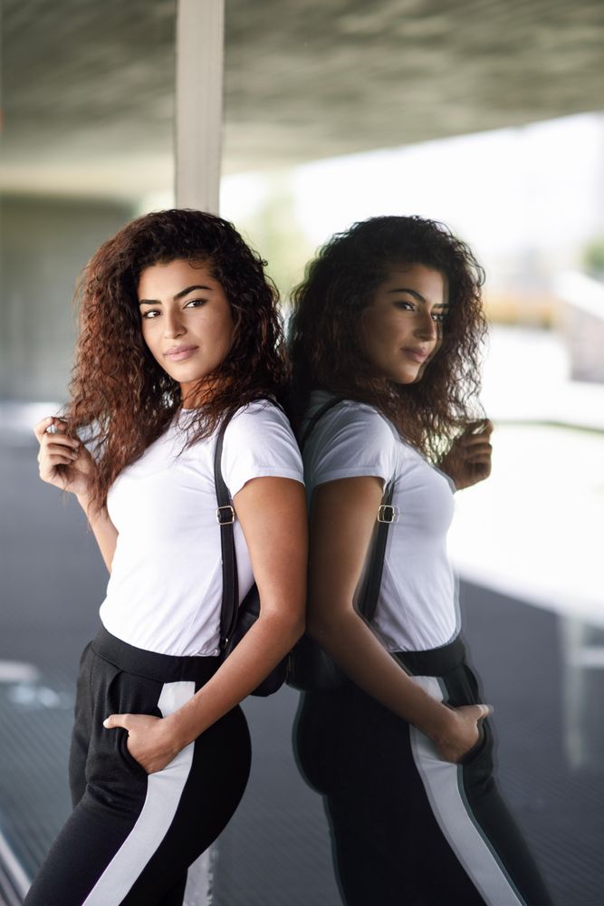 Arab woman leaning back against window of office building, copy space