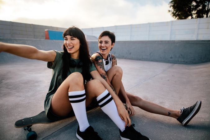 Smiling female friends hanging out at skate park