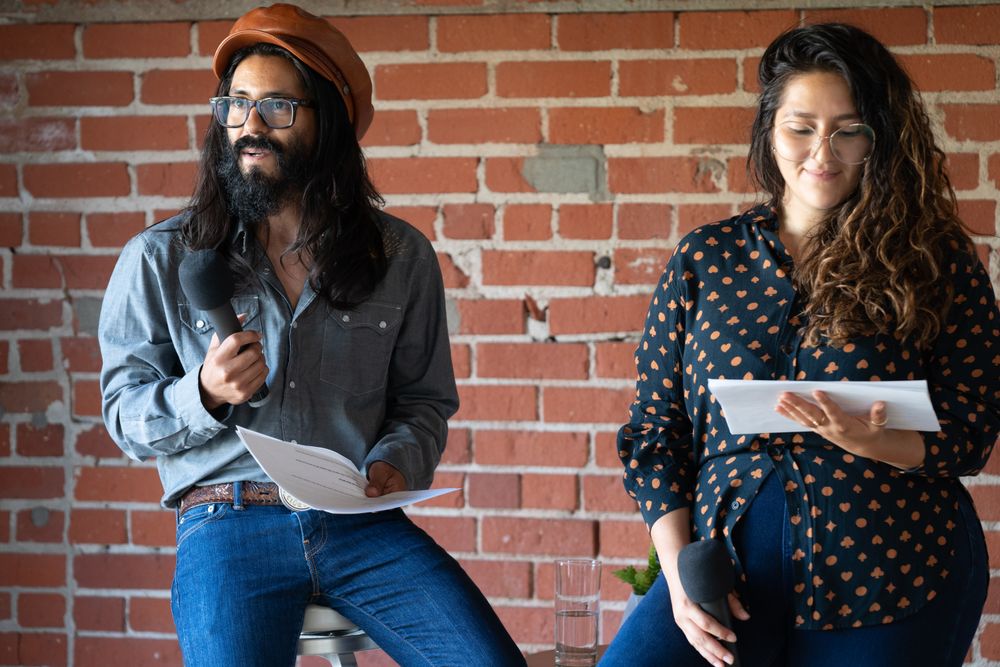 Man and woman holding their notes and a microphone while giving a talk