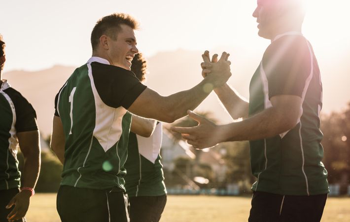 Rugby winning team players shaking hands and smiling after winning the game