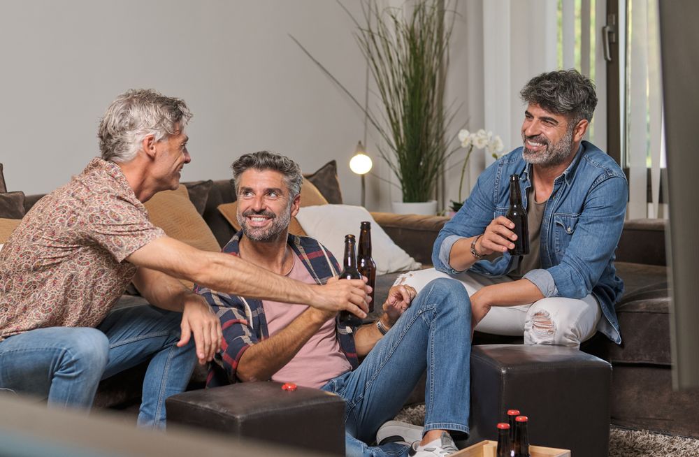 Cheerful men drinking beer and joking at home