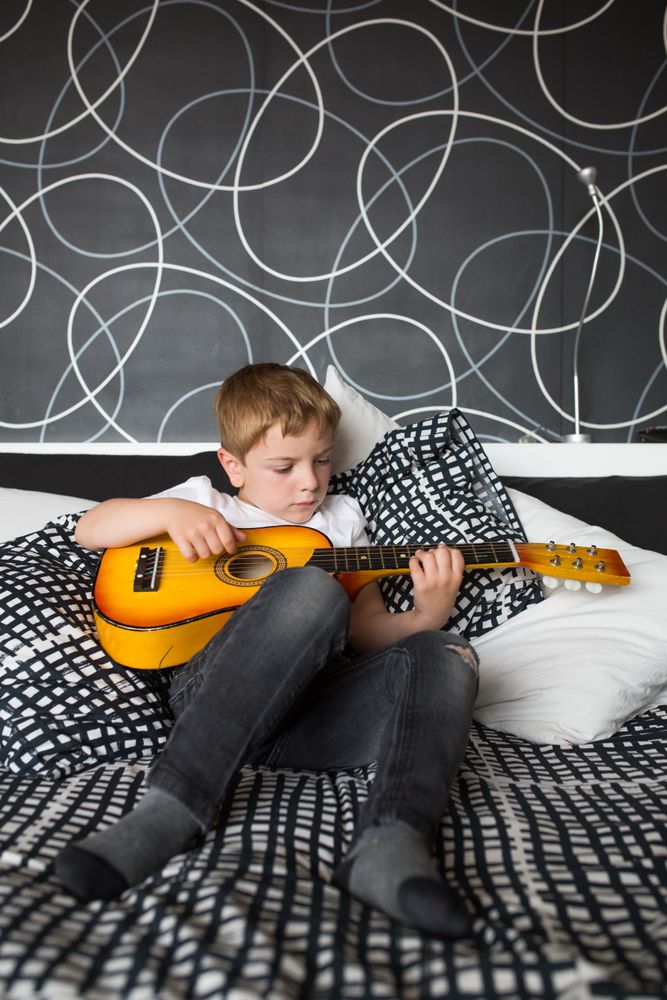 Young blonde boy playing toy guitar