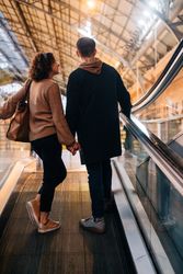 Young couple riding travelator in mall