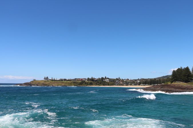Scenic coastal view of a tranquil bay with gentle waves and clear blue skies in a picturesque town
