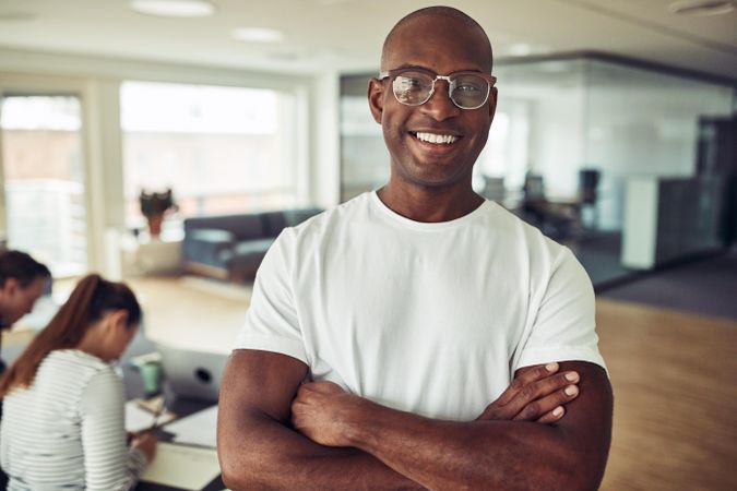 Portrait of Black business man smiling in an office with his arms crossed