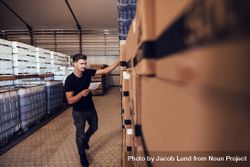 Young man tracking stock of packaged beer boxed in warehouse 0gjz3b