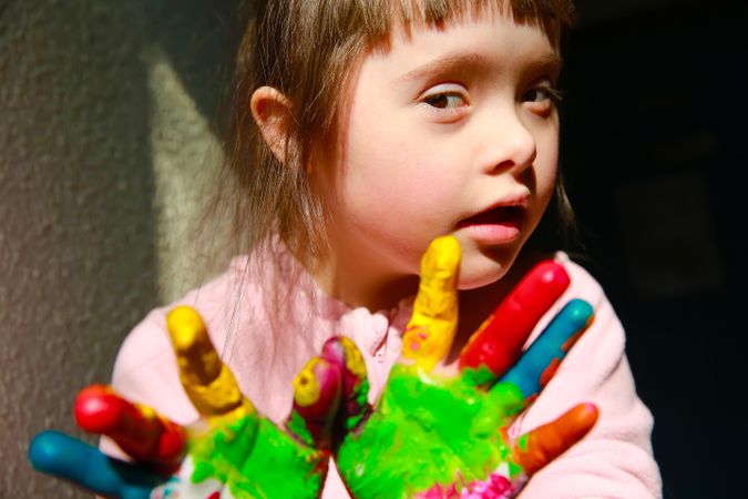 Cute young girl holding painted hands out to camera
