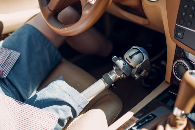 Cropped image of a man with prosthetic leg riding a car