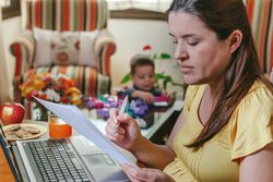 Mother working at home while her son plays