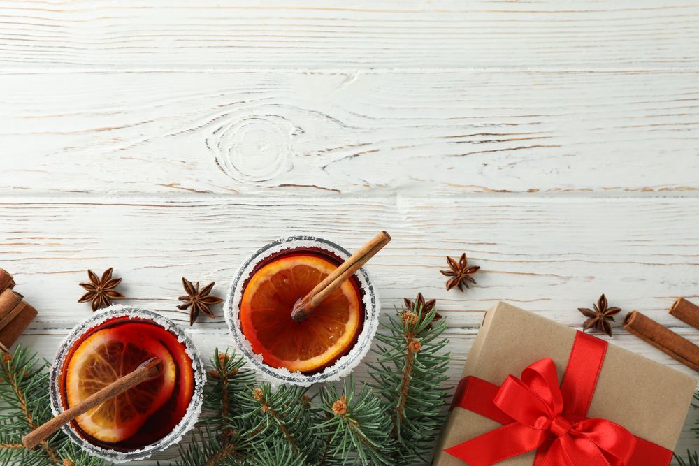Glasses of tasty mulled and gift on wooden background, top view