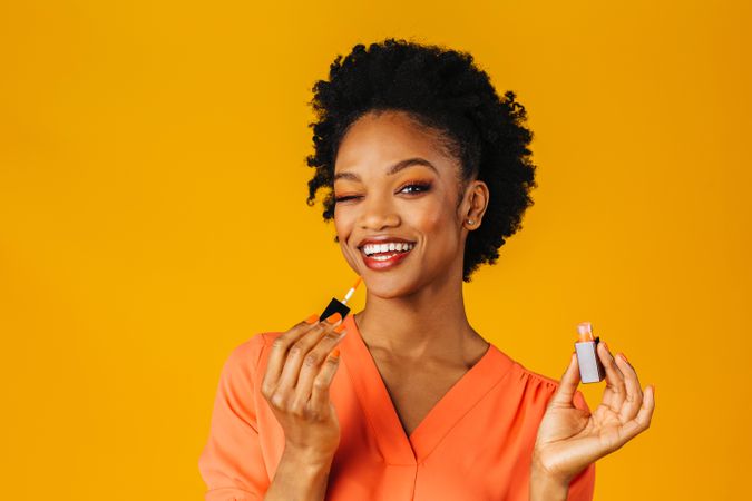 Playful Black woman smiling and applying lip gloss