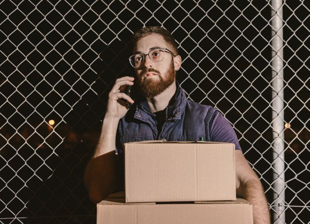 Courier with carton waiting client on street in evening
